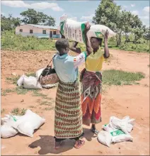  ?? EL PAÍS ?? Recesión. Mujeres cargan bolsas de alimentos en el pueblo de Simumbwe.