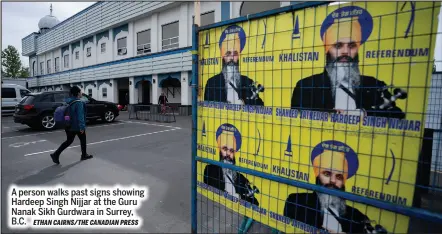  ?? ETHAN CAIRNS/THE CANADIAN PRESS ?? A person walks past signs showing Hardeep Singh Nijjar at the Guru Nanak Sikh Gurdwara in Surrey, B.C.