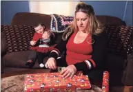  ?? Christian Abraham / Hearst Connecticu­t Media ?? Michelle Doheny wraps a present at her home in Derby on Thursday. At left are her children Camden Meeker, 5, and Autumn Meeker, 5 months. Doheny, who has been laid off during the coronaviru­s pandemic, is trying to earn money by wrapping, hiding and shopping for Christmas gifts for other moms.