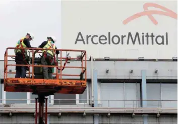  ?? — Reuters ?? Workers clean the facade of ArcelorMit­tal steel company, in Middleburg, South Africa, in this file photo.