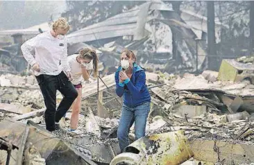  ?? [JEFF CHIU/THE ASSOCIATED PRESS] ?? Mary Caughey, center in blue, reacts with her son Harrison, left, after finding her wedding ring in debris at her home destroyed by fires on Tuesday in Kenwood, Calif.