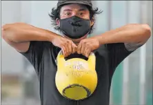  ?? Jeff Chiu Th e Associated P ress ?? T im Robles wears a mask while working out with a kettlebell last week at Fitness SF T ransbay gym in San Francisco.