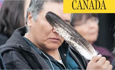  ?? JONATHAN HAYWARD / THE CANADIAN PRESS ?? Terry Ladue holds an eagle feather to his face after delivering powerful testimony about losing his mother to the National Inquiry into Missing and Murdered Indigenous Women and Girls in Whitehorse.