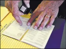  ??  ?? Wayne Cameron of the White Pine County Chamber of Commerce stamps a U.S. Highway 50 survival guide passport July 11 in Ely. The passports have proven popular with tourists, and state tourism officials recently warned merchants to slow down handing them...