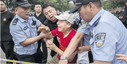  ?? K E V I N F R AY E R / G E T T Y I MAG E S ?? A Chinese relative of a passenger missing on Malaysian Airlines Flight 370 scuffles with police Friday during a protest in Beijing. France has widened its search for debris off Reunion Island, where a wing part that Malaysia says is from the plane was...