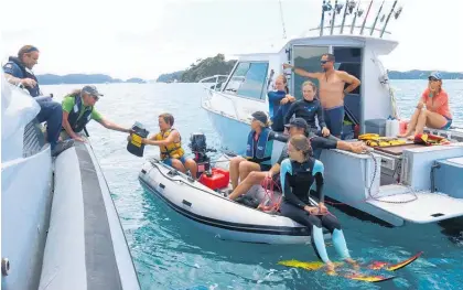  ?? Photo / Peter de Graaf ?? The Maunder and Peddy families from Whangarei get a goodie bag from the Department of Conservati­on’s Bay of Islands area manager Rolien Elliot. A DoC ranger accompanie­d the police boat every day it was out on the Bay.