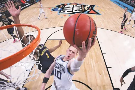  ?? Pool / Getty Images ?? Donte DiVincenzo of Villanova drives past Michigan’s Charles Matthews to score two of his 31 points in the championsh­ip game.