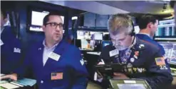  ?? —AP ?? NEW YORK: Specialist Brian Fairbrothe­r, left, works with traders at the post that handles Kroger on the floor of the New York Stock Exchange.
