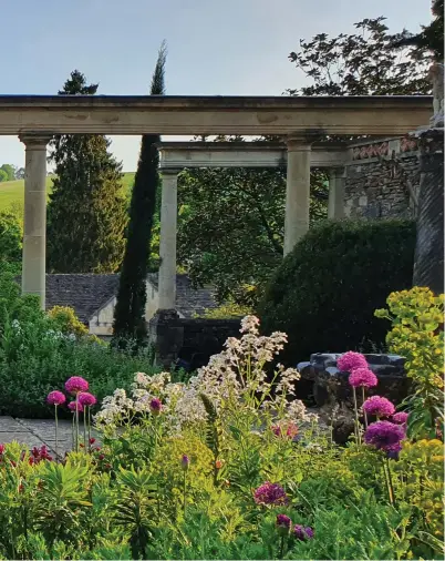  ??  ?? Pictured above:
A view across the valley from the wisteria-clad colonnade on the Great Terrace, with Aslan, one of the Manor's three cats, and a 19th-century copy of Rome's she-wolf statue.