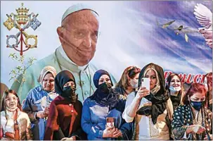  ?? ANDREW MEDICHINI / AP ?? Women wait outside the Chaldean Cathedral of Saint Joseph, in Baghdad, Iraq, on Saturday where Pope Francis, depicted on a giant poster at their back, is celebratin­g a Mass.
