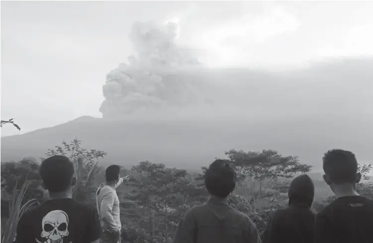  ?? (AP PHOTO/FIRDIA LISNAWATI) ?? VILLAGERS watch the Mount Agung volcano erupting during sunrise in Karangasem, Bali island, Indonesia, Sunday, Nov. 26, 2017. A volcano on the Indonesian tourist island of Bali erupted for the second time in a week on Saturday, disrupting internatio­nal...