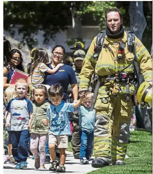  ?? — AP ?? Fleeing to safety: Rescue personnel escorting children from Academy on the Hill pre-school in Aliso Viejo after the fatal explosion nearby.