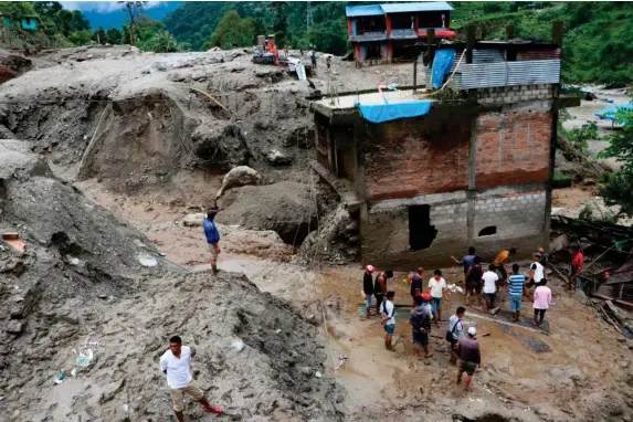  ??  ?? Rescuers search for survivors after a landslip in Jambu village, 80km northeast of Kathmandu (AFP)