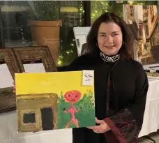  ?? Khaled Yacoub Oweis / The National ?? Prof Karen Fisher holds a painting by a Syrian refugee living in the Zaatari refugee camp