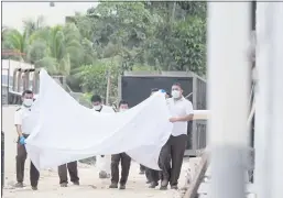  ?? KARIM TORRES — THE ASSOCIATED PRESS ?? Police hold a bed sheet in an attempt to block onlookers after an armed confrontat­ion close to a hotel near Puerto Morelos, Mexico, on Thursday.