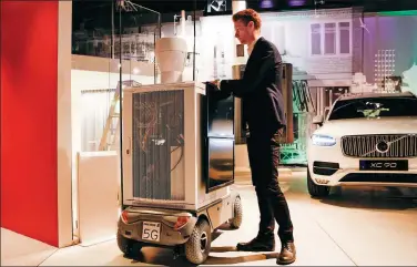  ?? BLOOMBERG ?? A visitor inspects a wheeled 5G base station prototype device on display at the headquarte­rs of Ericsson AB in Kista, Sweden.