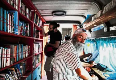  ??  ?? Books
galore: A man looking on as he sits inside a library van in central Athens. — AFP