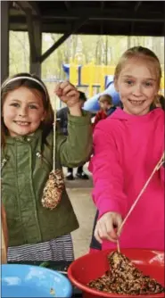  ??  ?? Seven-year-old Kylie Murphy and 9-year-old Abby Burns make peanut butter and seed bird feeders.