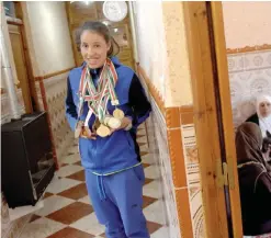  ??  ?? RELIZANE: Fethia Bekhedda of “Afak Relizane” poses for a picture with her medals at her home on February 17, 2017, in the Algerian city of Relizane. — AFP