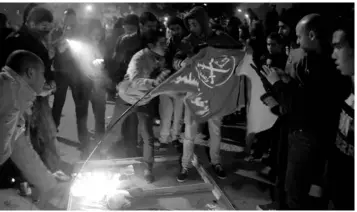  ??  ?? Unknown men gesture and celebrate as they try to burn a flag outside the Muslim Brotherhoo­d heaquarter after unkown attackers ransacked it and tried to set it on fire in Cairo.