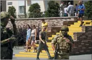  ?? ASSOCIATED PRESS ?? People walk past as Russian soldiers guard an office for Russian citizenshi­p applicatio­ns, in Melitopol, south Ukraine, July 14.