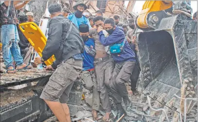  ?? Azhari Surahman The Associated Press ?? Rescuers assist a survivor pulled out from the rubble of a government building Friday in Mamuju, Indonesia, that collapsed during an earthquake. A strong, shallow quake shook Sulawesi just after midnight Friday, toppling homes and buildings.