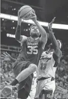  ?? CHARLIE RIEDEL/AP ?? OU forward Tanner Groves (35) shoots under pressure from OSU forward Moussa Cisse (33) during the first half of a 57-49 loss Wednesday in the Big 12 men’s basketball tournament in Kansas City, Mo.