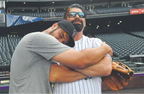  ??  ?? Rockies third baseman Nolan Arenado hugs former Colorado star Todd Helton during batting practice Friday.