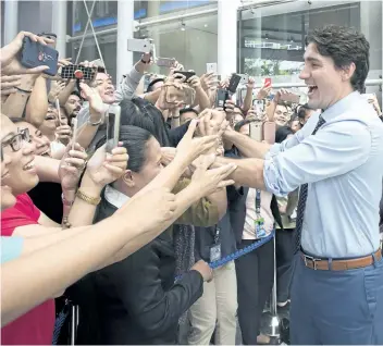  ?? ADRIAN WYLD/THE CANADIAN PRESS ?? Prime Minister Justin Trudeau shakes hands as he walks through a building’s lobby in Manila, Philippine­s, on Monday.