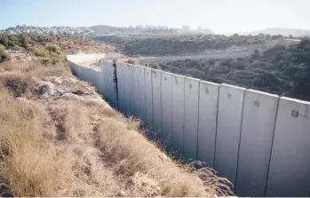  ?? NASSER NASSER/AP ?? A section of a barrier between the Israeli settlement of Modi’in Illit, right, and the West Bank village of Nilin.