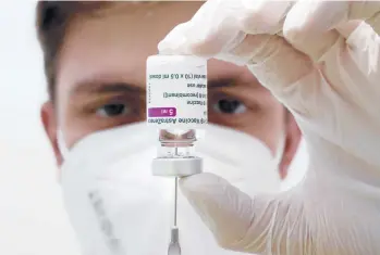  ?? MATTHIAS SCHRADER/AP ?? A medical worker prepares a syringe from a vial of the AstraZenec­a coronaviru­s vaccine Monday at a vaccinatio­n center in Ebersberg, Germany. The vaccine has been approved for use in Europe.