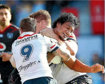  ?? PHOTO: GETTY IMAGES ?? It takes two Roosters to stop Warriors forward James Gavet charging downfield during the match in Auckland yesterday.