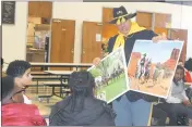  ??  ?? Hardrick Crawford of the Greater Washington D.C. Chapter of the 9th and 10th (Horse) Cavalry Associatio­n shows re-creation pictures of “Buffalo Soldiers,” African American units that helped drive westward expansion in the late 19th Century, to Benjamin...