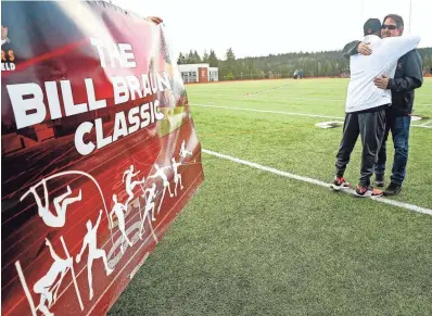  ?? MEEGAN M. REID/KITSAP SUN ?? Retired throws coach Bill Braun, right, hugs Central Kitsap track and field head coach Neal Gaulden after Gaulden unveiled the banner at left on Friday proclaimin­g that the Cougars’ first home meet each spring will now be known as the Bill Braun Classic.