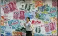  ?? KIN CHEUNG — THE ASSOCIATED PRESS ?? A woman walks by a money exchange shop decorated with currency banknotes at Central, a Hong Kong business district, Tuesday.