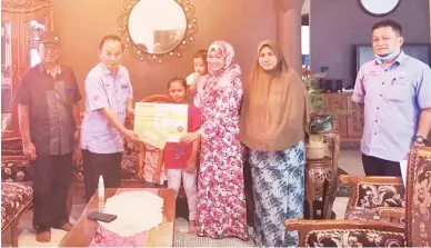  ??  ?? BANTUAN: Joseph menyampaik­an wang faedah kepada isteri Nurul Maslan.