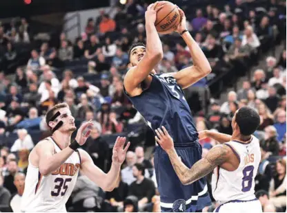  ?? AP ?? Karl Anthony Towns se dispone con fiereza a anotar dos puntos para los Wolves ante la oposición de dos defensas de los Soles.