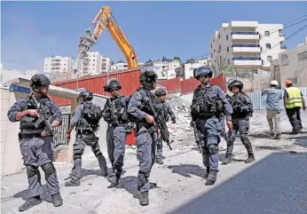  ??  ?? Israeli policemen look on as the home of a Palestinia­n family is demolished by Jerusalem municipali­ty in the mostly Arab East Jerusalem neighbourh­ood of Al Tur. The municipali­ty says Palestinia­n homes built without an Israeli permit will be torn down