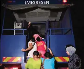  ??  ?? PORT DICKSON: In this file picture taken late July 11, 2017, detained foreign workers board a truck following a raid by Malaysian immigratio­n authoritie­s at a constructi­on site. —AFP