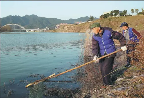  ?? HOU LIQIANG / CHINA DAILY ?? Workers remove rubbish from the Xiuhe River near the center of Xiushui, a county in East China’s Jiangxi province. In December, the central government released a document ordering the river chief system, which is linked to performanc­e evaluation­s of...