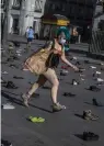  ?? — AP ?? A member of the Extinction Rebellion group walks among shoes during the performanc­e “Covid today, climate crisis tomorrow”, at Sol Square in Madrid on Friday.