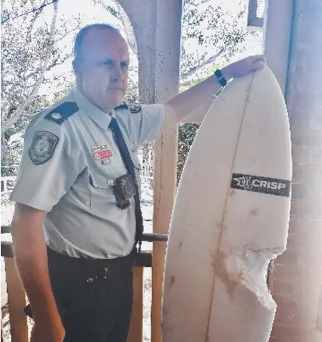  ??  ?? Detective Inspector Matt Kehoe, Officer in Charge at the Byron Bay Police Station, with the surfboard showing the bite.