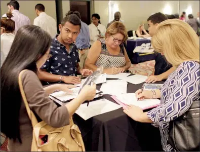  ?? AP/ LYNNE SLADKY ?? Job seekers fi ll out applicatio­ns at a career event in July in Miami Lakes, Fla. The low level of applicatio­ns for jobless benefi ts suggests employers likely are looking to add workers, analysts say.