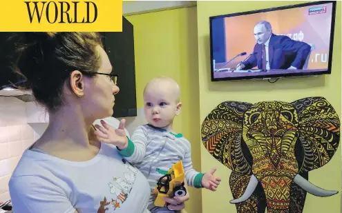  ?? YURI KADOBNOV / AFP / GETTY IMAGES ?? A woman watches a TV broadcast of Russian President Vladimir Putin’s annual press conference in Moscow on Thursday.