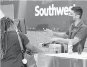  ?? TONY GUTIERREZ/AP ?? Southwest Airlines employee Oscar Gonzalez, right, assists a passenger June 24 at Love Field in Dallas.