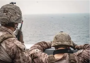  ?? (US Navy/Reuters) ?? US MARINES onboard the ‘USS John P. Murtha’ watch nearby Iranian fast inland attack craft, as they transit the Strait of Hormuz earlier this week.