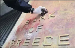  ?? JOHN KOLESIDIS Reuters ?? A worker cleans the facade of the Bank of Greece in Athens on Thursday. Greece expressed hope it was within days of securing a bailout.