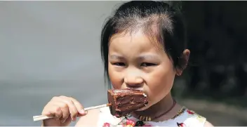  ?? MICHELLE BERG ?? Six-year-old Cici Hu eats cheesecake on a stick on the last day of Taste of Saskatchew­an at Kiwanis Park in Saskatoon Sunday.