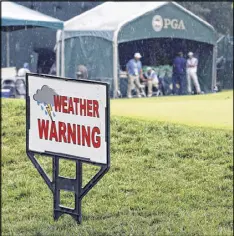  ?? TONY GUTIERREZ / AP ?? Tournament workers wait in a tent near the practice green. After Saturday’s deluge, they’ll have their hands full preparing the course for play today.