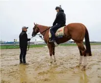  ?? LLOYD FOX/BALTIMORE SUN ?? Assistant trainer Jose Hernandez stands with Good Magic as exercise rider Walter Malasquez waits for his turn to take the horse around the Pimlico track.